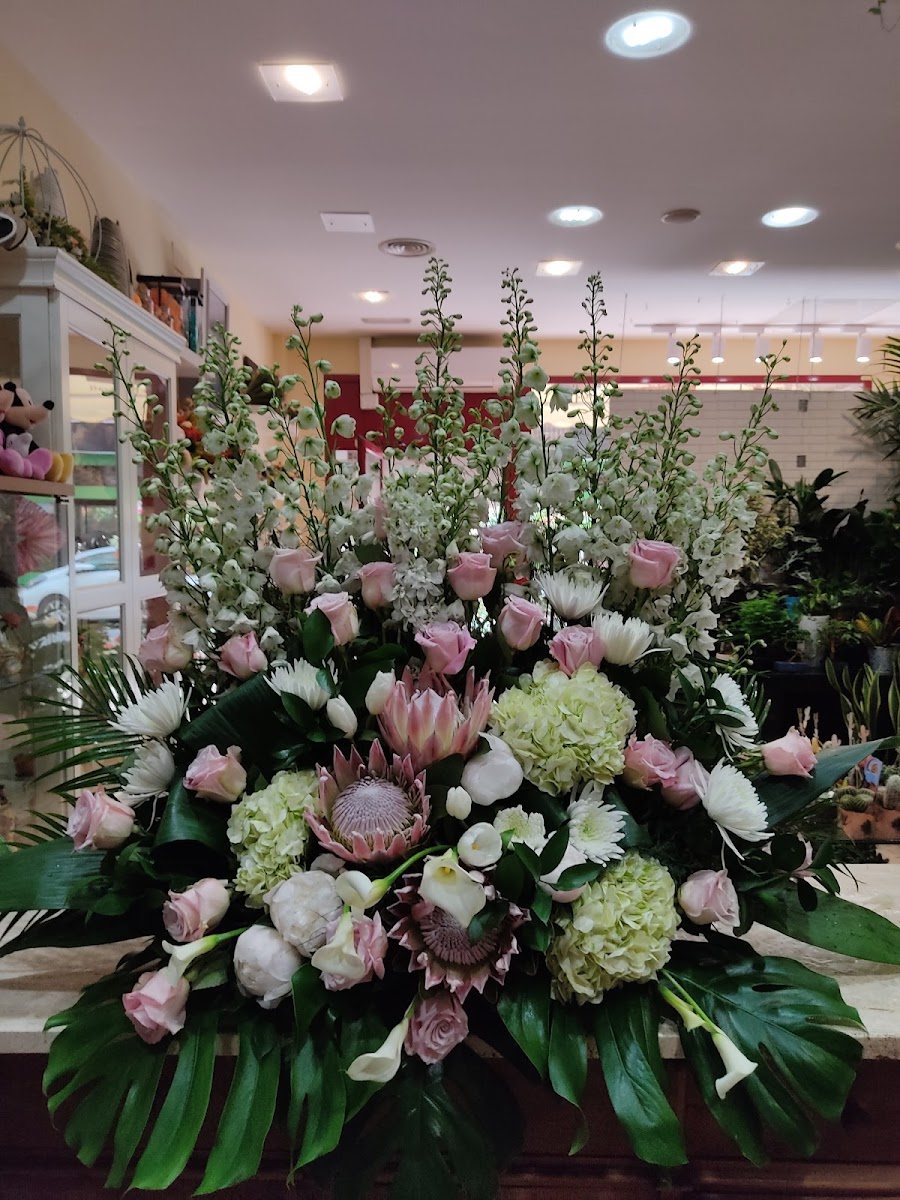 Gran centro de protea, rosas rosas, hortensia y espuela de caballero en el mostrador de la tienda